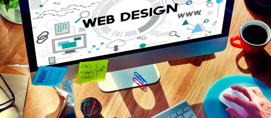 A web design workspace with a monitor showing website plans